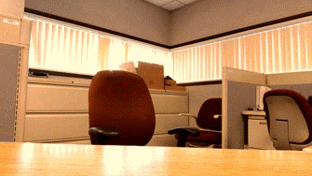 a cubicle with two chairs and a window with blinds on it