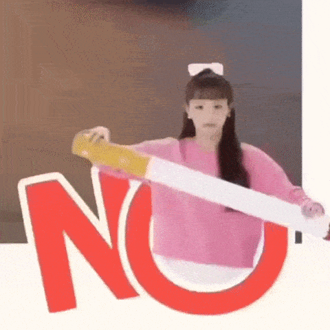 a woman in a pink sweater is holding a large cigarette in front of a no sign .