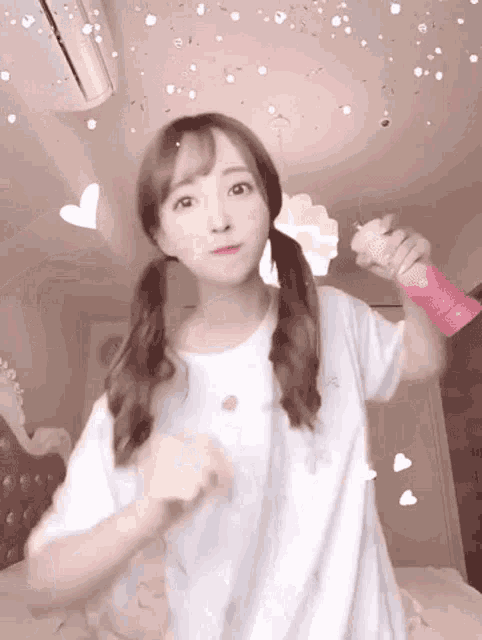 a girl in a white shirt is holding a pink bottle in her hand and making a funny face .