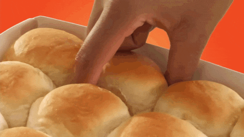 a person 's hand is reaching into a box of rolls