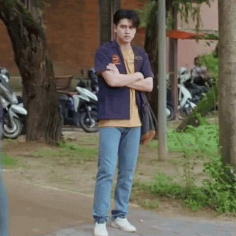 a man is standing on a sidewalk with his arms crossed in front of motorcycles .