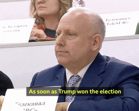 a man in a suit and tie holding a sign that says as soon as trump won the election