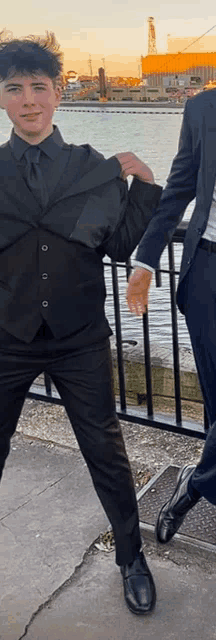 a man in a suit holds the arm of a young boy in a black suit
