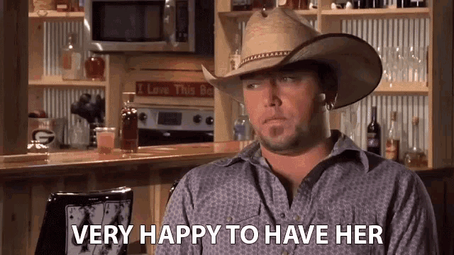 a man wearing a cowboy hat is very happy to have her