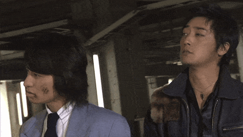 a man in a suit and tie is standing next to another man in a jacket
