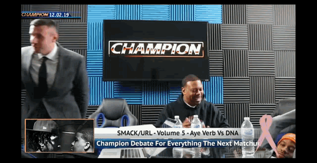 a man in a suit and tie is sitting in front of a champion sign