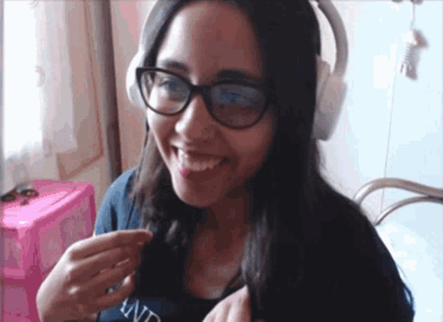 a girl wearing glasses and headphones is smiling and holding her hair