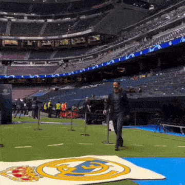 a man in a suit walks across a soccer field