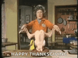 a woman is holding a dead turkey on a cutting board and says happy thanksgiving .