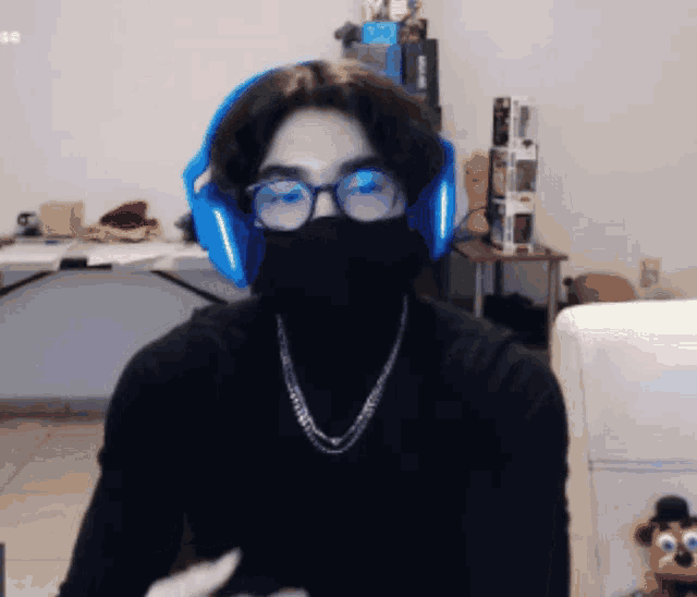 a man wearing a black turtleneck and blue headphones is looking at the camera