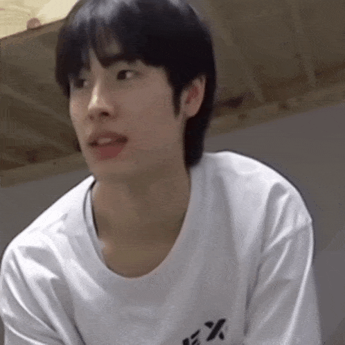a young man wearing a white shirt with the letter x on the front
