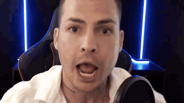 a man is sitting in front of a microphone with his mouth open .