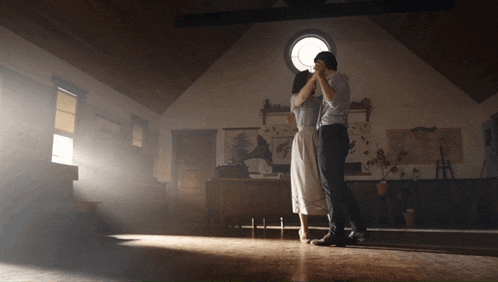a man and a woman are dancing in a room with a window