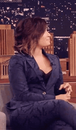 a woman in a suit is sitting on a couch and smiling