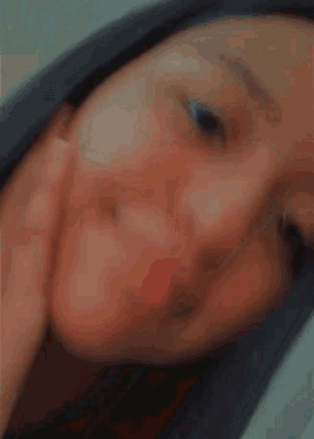 a blurry picture of a woman 's face with her hand on her cheek
