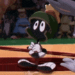 marvin the martian is sitting on a baseball field holding a baseball bat .