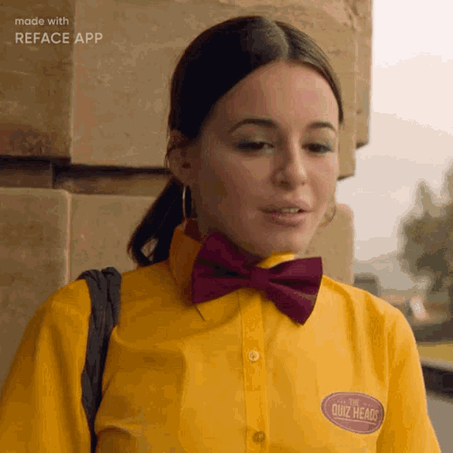 a woman wearing a yellow shirt and a purple bow tie has a quiz heads badge on her chest