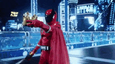 a red super hero is holding a crown and a sword .