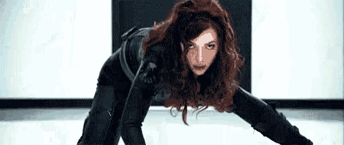 a woman in a black suit is kneeling down on the floor in a room .
