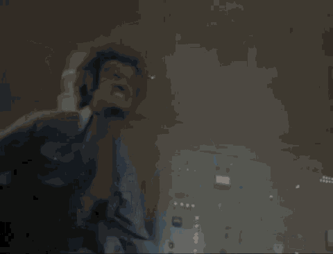 a man in a suit and tie is standing in a dark room with smoke coming out of the ceiling .
