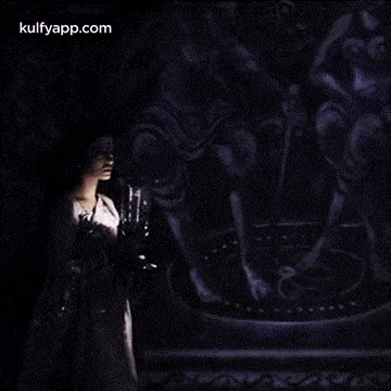 a woman in a white dress is standing in a dark room with a painting in the background .