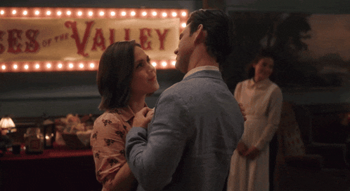 a man and woman are dancing in front of a sign that says " valley "