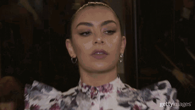 a close up of a woman wearing a floral shirt and earrings