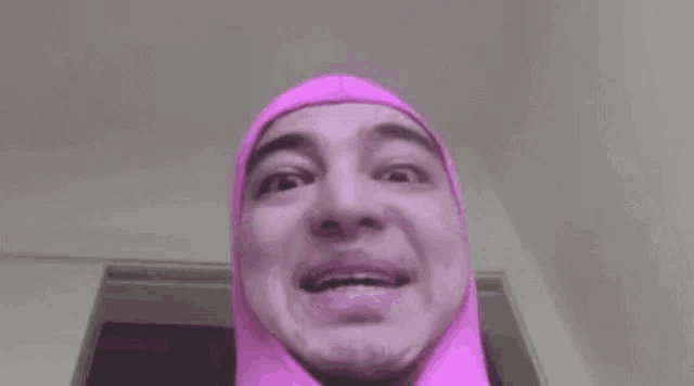a close up of a person wearing a pink hijab with their mouth open .