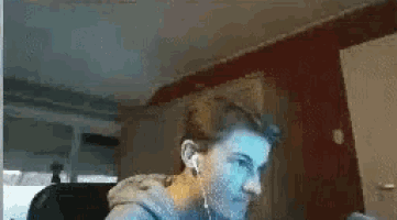 a man is sitting in front of a computer screen wearing headphones .