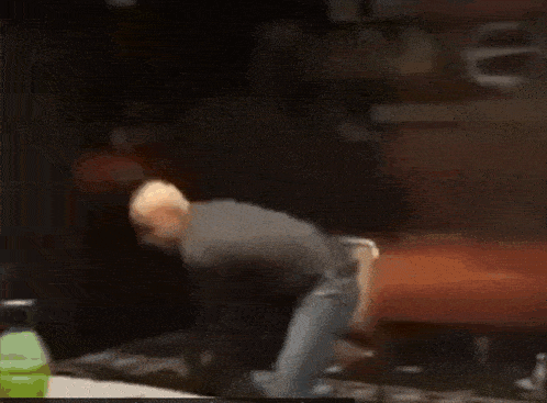 a man in a black shirt is dancing in front of a sign that says ' i love you ' on it .