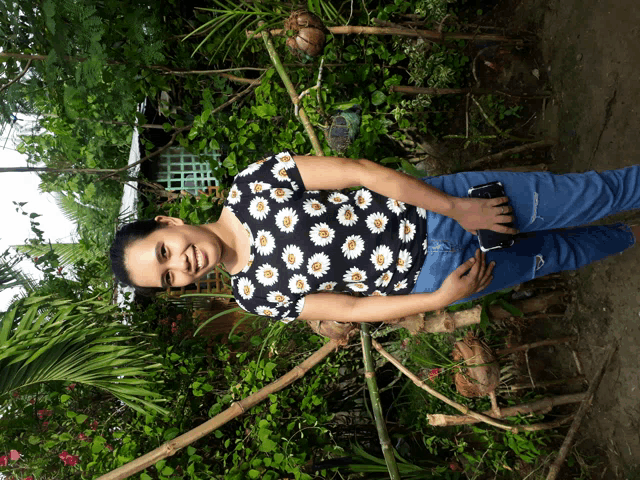 a woman wearing a daisy shirt is standing in a garden