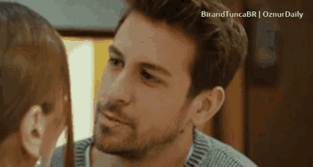 a man and a woman are looking at each other and the words birandtuncabr oznurdaily are visible
