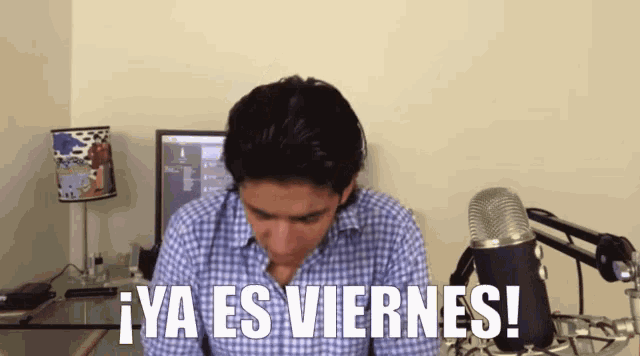 a man sitting in front of a microphone with the words ya es viernes on his shirt