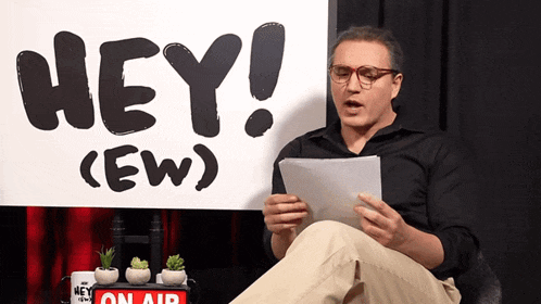 a man is sitting in front of a sign that says hey ( ew )