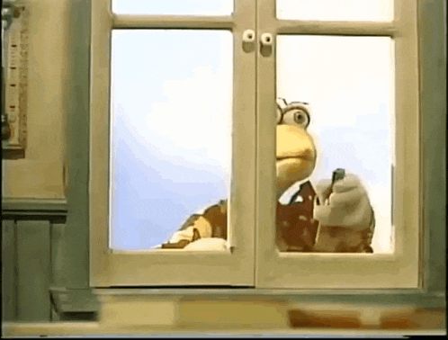 a puppet is looking out of a window while holding a bottle .