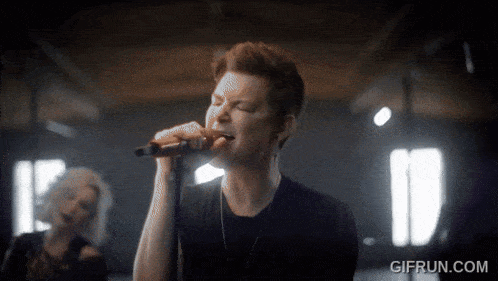 a man singing into a microphone with the website gifrun.com in the lower right corner