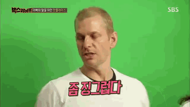 a man in a white shirt is talking in front of a green screen with sbs written on it .