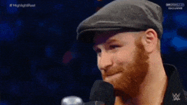a man with a beard is talking into a microphone on a wrestling show .
