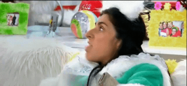 a woman is sitting on a couch with her mouth open in front of a table with pictures on it .