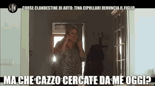 a woman in a leopard print shirt is talking on a cell phone in a hallway