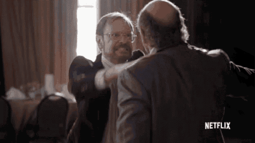 two men are hugging each other in a room with a netflix logo on the bottom .