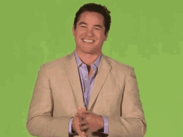 a man in a tan suit is laughing with his arms outstretched