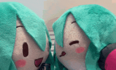 a couple of stuffed animals with green hair are sitting next to each other .