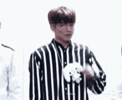 a man wearing a black and white striped shirt is holding a stuffed animal in his hand .
