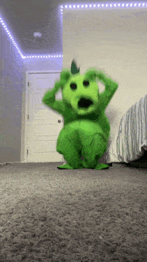a person in a green monster costume is standing on a carpet in a room .