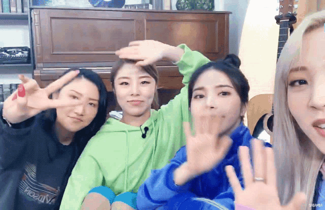 a group of young women are posing for a picture with their hands in the air and one of them has a ring on her finger