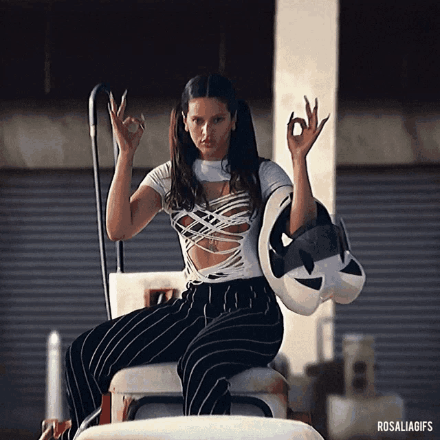 a woman is sitting on a motorcycle and giving the ok sign