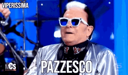 a man wearing sunglasses and a silver jacket says pazzesco on the screen