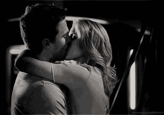 a black and white photo of a man and a woman kissing