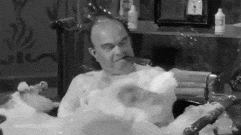 a man is taking a bath in a bathtub filled with soap bubbles .